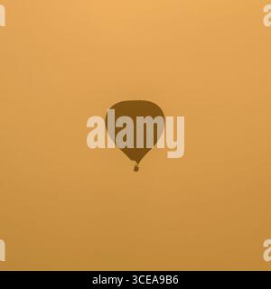 Hot air balloon at sunrise, silhouetted against the sky, taken on the Somerset levels, UK Stock Photo