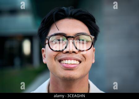 Young man wearing eyeglasses smiling outdoors, portrait of happiness Stock Photo