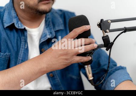 Focused young man speaking into a microphone while recording a podcast in a professional studio environment. Stock Photo