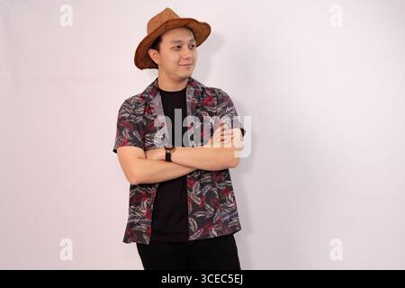 casual young man posing with crossed arms and wearing straw hat Stock Photo