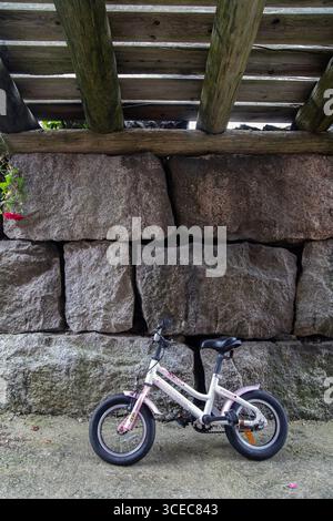Small two-wheeled children's bike parked under an old wooden bridge. photo: Bo Arrhed Stock Photo