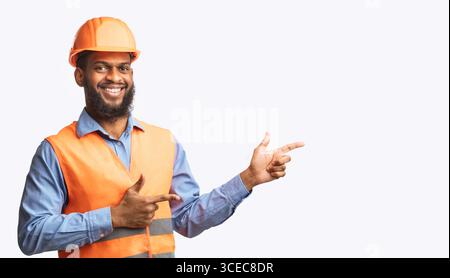 Builder Guy In Uniform Pointing Fingers Aside On White Background Stock Photo