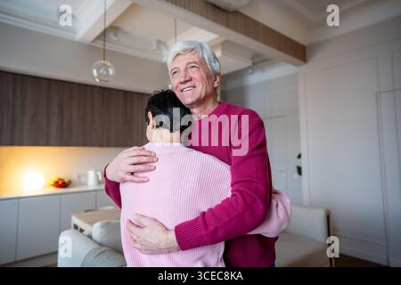 Smiling older man embracing consoling wife tenderly. Old couple relationship support, emotional bond Stock Photo