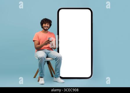 Cheerful curly eastern guy enjoying newest mobile app Stock Photo