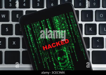 Closeup of hacked smartphone lying on laptop keyboard Stock Photo