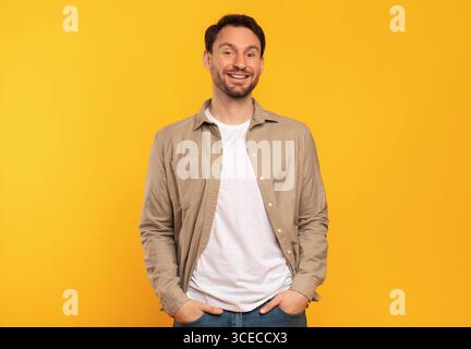 Smiling Man In Brown Shirt Standing Against Yellow Background Stock Photo