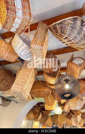 Interior ceiling of a rustic restaurant decorated with hanging wicker baskets and warm pendant lights. Cozy boho atmosphere Stock Photo