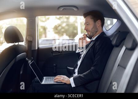 Busy entrepreneur working on laptop, talking on phone Stock Photo