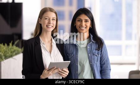 Two cheerful diverse colleagues standing in office together Stock Photo