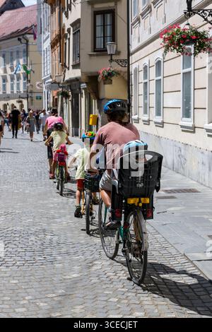 Ljubljana, Slovenia - August 15, 2019: Family rides bicycles on the street of Ljubljana Stock Photo