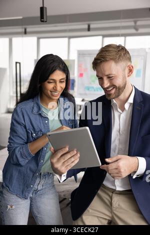 Two positive young diverse colleagues using digital tablet together Stock Photo