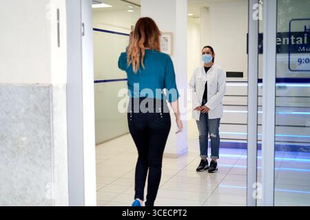 A dentist greets a patient in a modern dental clinic reception area. The space is equipped with contemporary design, showcasing a clean, professional Stock Photo