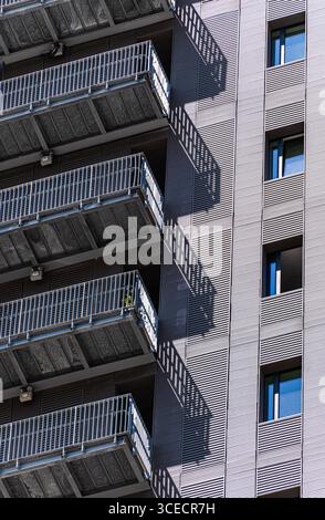 Close-up of a modern urban building facade with metal stairs casting shadows on the wall. The image highlights the architectural design and texture of Stock Photo