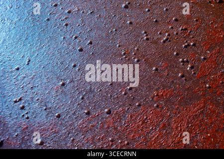 Close-up of a rusty metal surface showing natural weathering. The texture displays a range of earthy colors with pitted spots, giving it an industrial Stock Photo