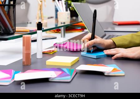 A creative workspace featuring hands writing on a blue notepad surrounded by colorful tools, showcasing a dynamic image consulting environment that sp Stock Photo
