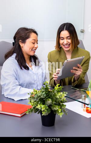 Two women engage in a consulting session, using a digital tablet for seamless communication. The focus is on collaboration and innovation in a modern Stock Photo