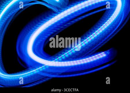 A captivating image of swirling blue light trails against a dark background, created using long exposure photography techniques to create a sense of d Stock Photo