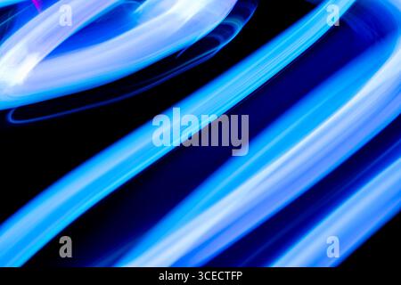 An abstract image showcasing dynamic blue light trails against a dark background. The motion blur creates a sense of movement and energy, enhancing th Stock Photo