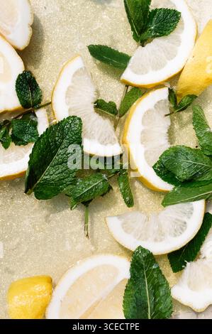 Refreshing lemon slices paired with vibrant mint leaves rest on a sparkling golden surface, creating an invigorating scene of freshness and zest, perf Stock Photo