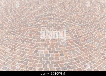 A detailed view of a cobblestone pavement, showcasing an intricate textured design with multi toned stone tiles. The harmonious arrangement enhances o Stock Photo