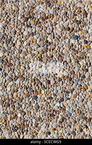 Stones of various shapes and colors are laid out on the road as a sidewalk close-up. Stock Photo