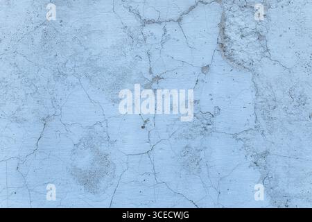 A close-up view of a weathered concrete surface displaying intricate cracks and texture, set in calming blue-gray tones. Ideal for backgrounds or desi Stock Photo