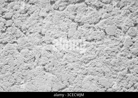 A detailed close-up image of a white concrete surface, showcasing its rough and intricate texture. The image highlights natural imperfections and a un Stock Photo