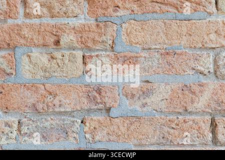 Close-up view of a textured brick wall with prominent rough surface patterns. The bricks exhibit a natural, tactile quality with a rugged appearance. Stock Photo