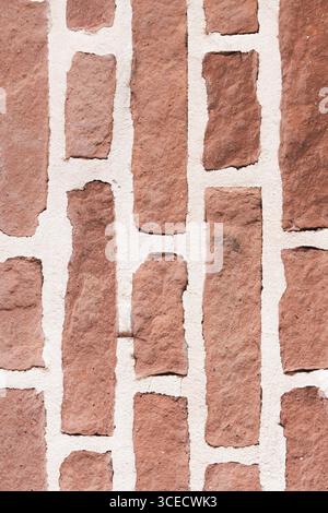 A close-up image showcasing a textured red brick wall with visible mortar lines. The rough surface highlights the intricate details and patterns of th Stock Photo
