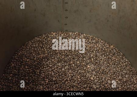 A close-up view of freshly roasted coffee beans resting inside an industrial coffee roasting drum. The beans exhibit a rich brown color, indicating pe Stock Photo
