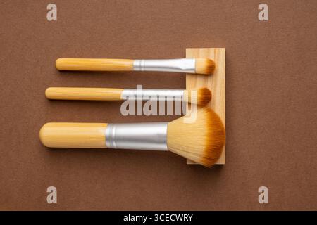 Top view of eco-friendly bamboo toothbrushes, sponges, and soap on a wooden surface. The brown wood background adds an earthy touch to this zero-waste Stock Photo