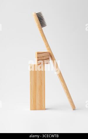 A natural bamboo toothbrush elegantly leans against two stacked wooden blocks. The minimalist design highlights eco-friendly materials against a light Stock Photo