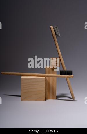 Bamboo toothbrushes artistically arranged with wooden blocks on a smooth gray surface, reflecting an eco-friendly lifestyle and minimalist aesthetic i Stock Photo