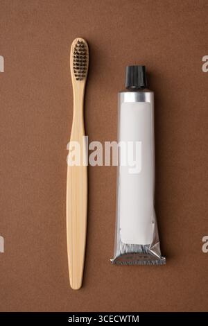 Top view of a bamboo toothbrush and a toothpaste tube on a brown paper background. The image highlights eco-friendly dental care products with a focus Stock Photo