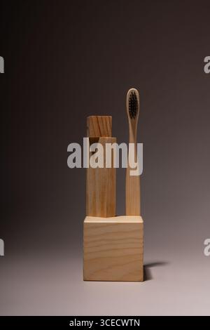 Bamboo toothbrush and geometric wooden blocks arranged artistically on a neutral background, promoting sustainable living and minimalist decor with ec Stock Photo