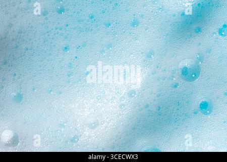 Close-up image showcasing a vibrant blue foam texture, highlighting numerous small and large bubbles. The intricate pattern creates a soothing, calmin Stock Photo