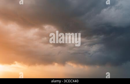 A dramatic view of storm clouds covering the sky in Alcarria, Spain, during sunset. The mix of dark clouds and warm hues creates a stunning contrast, Stock Photo