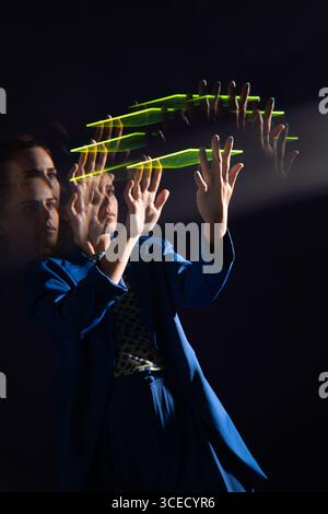 A young woman interacts with a glowing futuristic device, demonstrating a cutting-edge technological concept in a dark environment, showcasing innovat Stock Photo