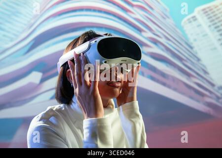 A Latin woman wearing virtual reality glasses is deeply immersed in a digital experience, exploring new realms with advanced technology in a modern, f Stock Photo