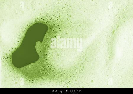 A detailed macro photograph showcasing the vibrant green texture of matcha foam. Tiny bubbles and rich color create an intriguing abstract pattern on Stock Photo