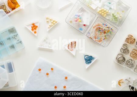 Top view of a jewelry making studio setup featuring various beads and rings in organized containers. Essential materials for crafting handmade jewelry Stock Photo
