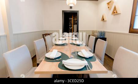 A neatly arranged dining table in a restaurant, prepared for a meal, featuring elegant decor with white plates, napkins, and cutlery on a wooden table Stock Photo