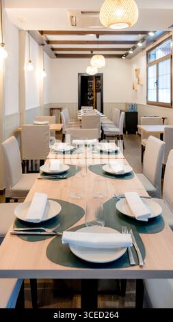 Elegant restaurant interior featuring neatly arranged tables with elegant dinnerware, soft lighting, and comfortable seating, creating a cozy and invi Stock Photo