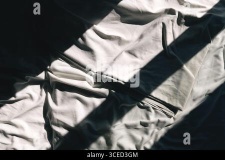 Shadow and light pattern on crumpled cotton bedsheet, top view Stock Photo