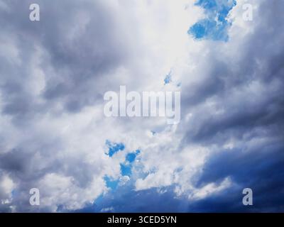 Dramatic sky with dark, moody clouds breaking to reveal patches of blue. Evokes feelings of hope, change, or resilience. Perfect for backgrounds, insp Stock Photo