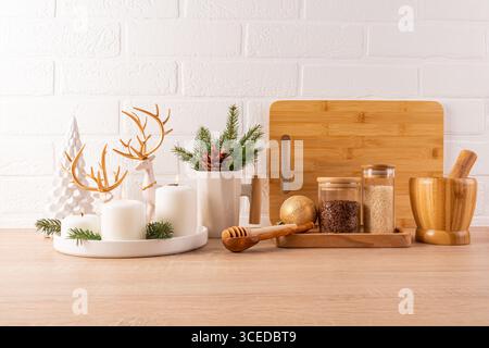 Beautiful kitchen background of Christmas kitchen countertop with spice jars, mortar and pestle, dish with candles and reindeer. Front view Stock Photo