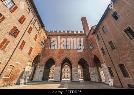 Wide-angle view of the historic Palazzo Gotico courtyard in Piacenza, Italy, showing Gothic arches, red brick walls, and medieval details Stock Photo