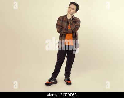 pensive young man posing casually in a checkered shirt and comfortable shoes Stock Photo
