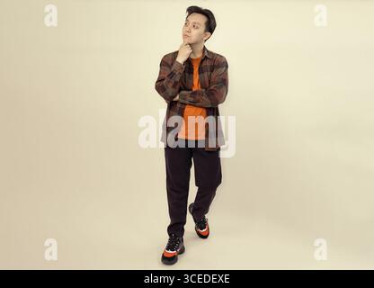 pensive young man posing casually in a checkered shirt and comfortable shoes Stock Photo