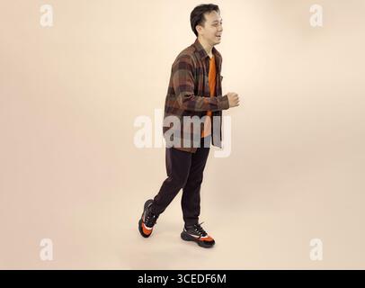 casual young man walking in style on beige background Stock Photo